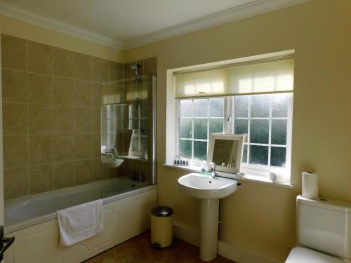 a bathroom with a sink and a tub and a window at Walma in West Runton