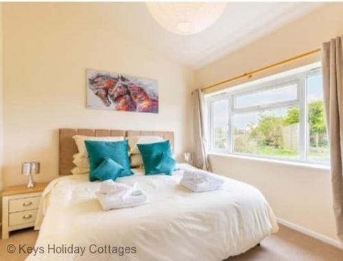 um quarto com uma cama com almofadas azuis e uma janela em The Paddocks em Frettenham