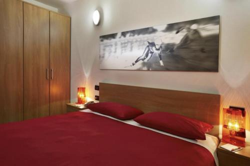 塞斯特雷的住宿－Villaggio Olimpico Sestriere，一间卧室配有红色的床和两个红色枕头