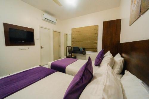 a hotel room with two beds and a flat screen tv at Hoppers Stop Yelahanka in Bengaluru
