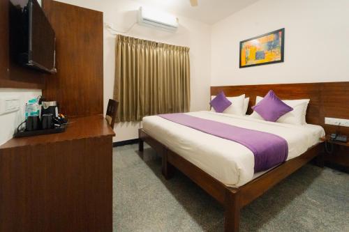 a hotel room with a large bed with purple pillows at Hoppers Stop Yelahanka in Bangalore