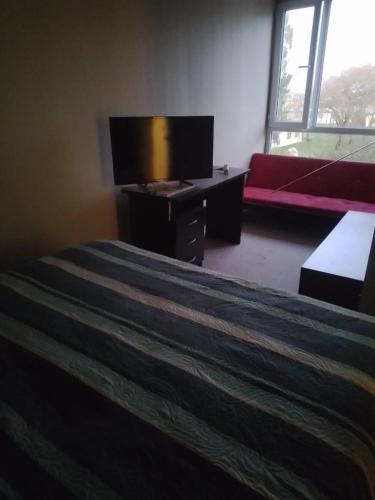 - une chambre avec un lit et une télévision à écran plat dans l'établissement Departamento en Condominio, à Puerto Montt