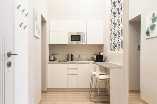 a kitchen with white cabinets and a counter with stools at Central Relax Boutique Suites in Budapest