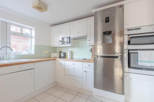 cocina con armarios blancos y nevera de acero inoxidable en Spacious 3BD Flat - 14 Mins to Buckingham Palace! en Londres