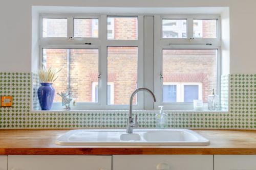 a kitchen counter with a sink and two windows at Spacious 3BD Flat - 14 Mins to Buckingham Palace! in London