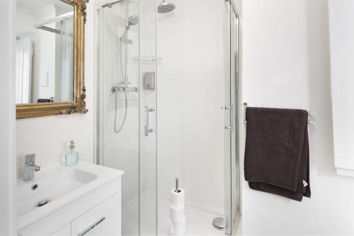 uma casa de banho branca com um chuveiro e um lavatório. em Home Sweet Home - Tejo em Lisboa