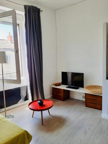 une chambre avec un tabouret rouge devant une télévision dans l'établissement Le Saint Jean, à La Rochelle
