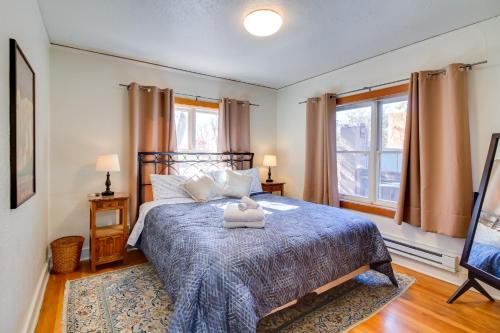 a bedroom with a bed with a blue comforter and two windows at Silver Hill Apartment Near UNM Campus! in Albuquerque