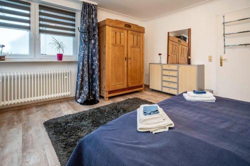 ein Schlafzimmer mit einem blauen Bett, einer Kommode und einem Fenster in der Unterkunft Boettcher's Ferienwohnung in Neulußheim