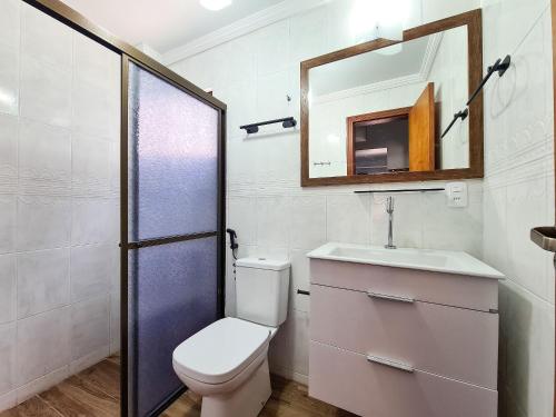 een badkamer met een toilet, een wastafel en een spiegel bij Residencial Itaguaçu in Bombinhas