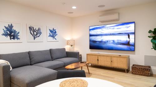 a living room with a couch and a flat screen tv at Surf Casita - Luxury Beach Home - Steps to Ocean & Walk to everything in Newport Beach