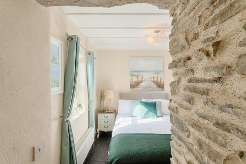 um quarto com uma cama e uma parede de pedra em The Boathouse On The Atlantic Sea em Liscannor