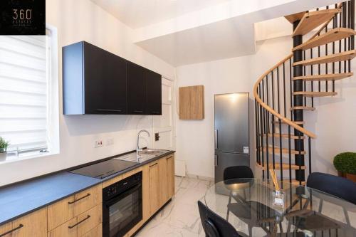 uma cozinha com uma mesa de vidro e uma escada em A lovely duplex maisonette just of Spinola w/WIFI by 360 Estates em St. Julian's