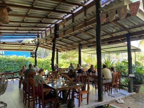 um grupo de pessoas sentadas em mesas em um restaurante em Suan Nai Kokut Resort em Ko Kood