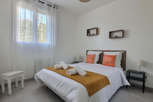 ein weißes Schlafzimmer mit einem großen Bett mit orangefarbenen Kissen in der Unterkunft *Au Bord du Canal*Entre Paris et Disneyland in Chelles