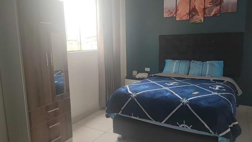1 dormitorio con 1 cama con edredón azul y ventana en HOSPEDAJE BLESS, en Trujillo