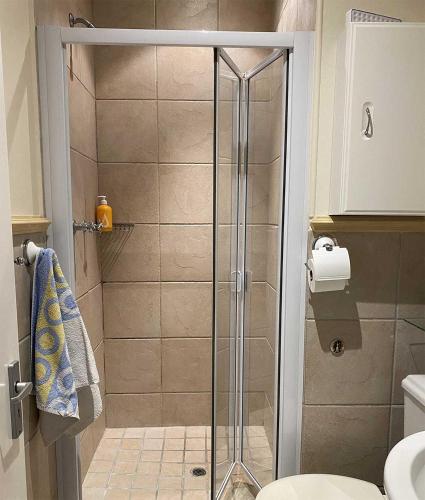 a shower with a glass door in a bathroom at On the Beach in Hout Bay