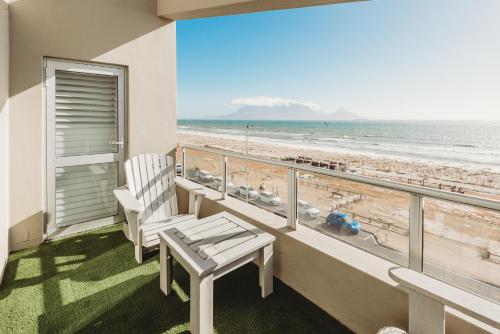 a balcony with a bench and a view of the beach at Voir la Mer - Blouberg Beach in Bloubergstrand