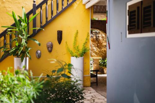 a yellow wall with potted plants next to a door at Bario Hotel in Willemstad