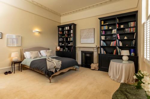 a bedroom with a bed and a fireplace and bookshelves at Pittville House in Cheltenham
