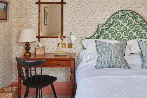 a bedroom with a bed and a desk with a mirror at Leonardslee House at Leonardslee Lakes & Gardens in Horsham