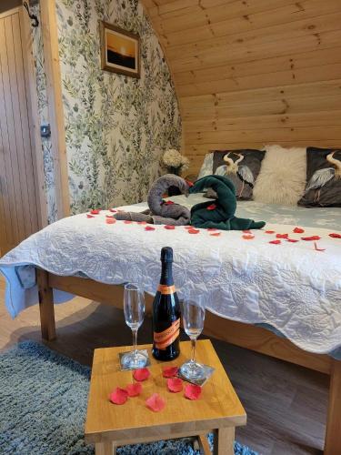 a bed with a bottle of wine and a table with wine glasses at The Galloway Steading - The Herons Nest, secure garden and with Hot Tub and Fire Pit in Glenluce