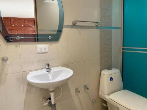 a bathroom with a sink and a toilet and a mirror at Casa 30 in Bogotá