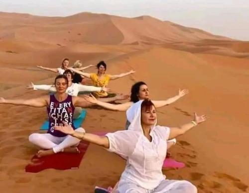 un grupo de mujeres haciendo yoga en el desierto en LODGE bennouri, en Telouet