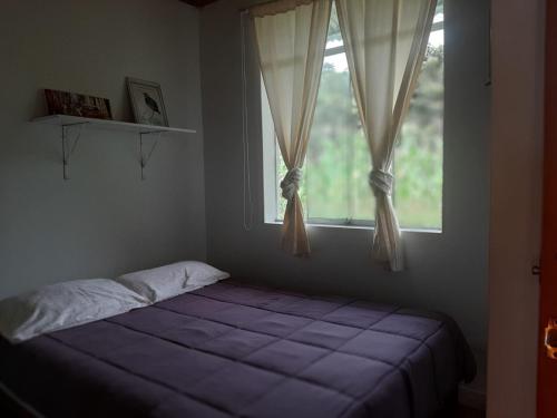 a bedroom with a bed in front of a window at Cabañitas Shollet in Oxapampa