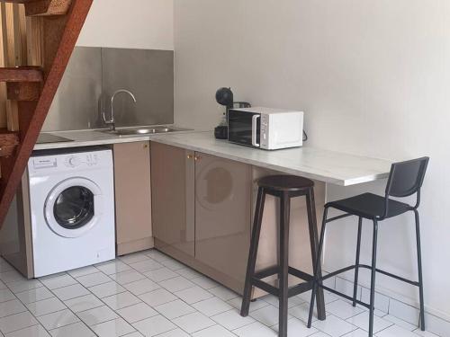 a kitchen with a counter with a microwave and a washing machine at Appart des airs Mamoudzou in Mamoudzou