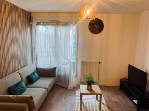 sala de estar con sofá y reloj en la pared en Charmant T2 moderne /proximité CDG / Confort en Villepinte