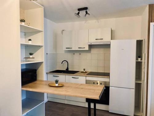 cocina con mesa de madera y nevera blanca en Charmant T2 moderne /proximité CDG / Confort, en Villepinte