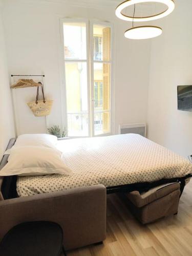 un lit dans une chambre avec une grande fenêtre dans l'établissement Très Joli Studio à 150 m de la mer, à Nice