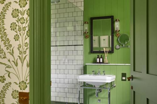 a green bathroom with a sink and a mirror at Leonardslee House at Leonardslee Lakes & Gardens in Horsham