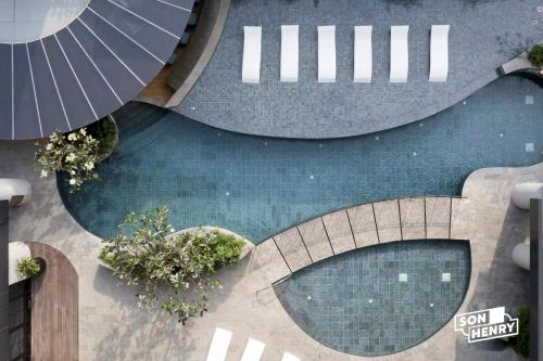 - une vue de tête sur deux piscines avec un parasol dans l'établissement Son&Henry Zenity District 1, à Hô-Chi-Minh-Ville