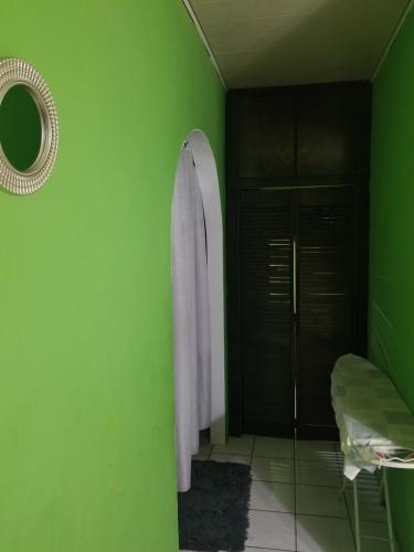 bagno con parete verde e specchio di Rouse Homestays a Couva