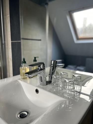 un lavabo de salle de bain blanc avec des verres dessus dans l'établissement HOTEL DE L'ABBAYE DE LONGPONT, à Longpont