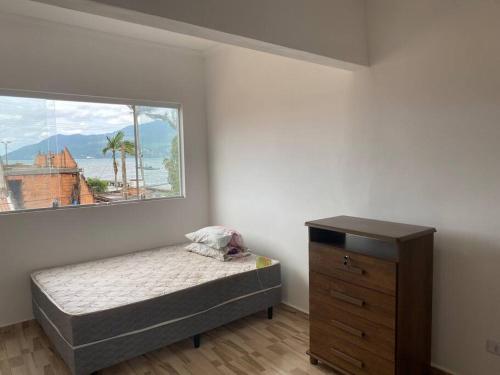 een slaapkamer met een bed, een raam en een dressoir bij Kitnet a 50 metros da Praia in São Sebastião