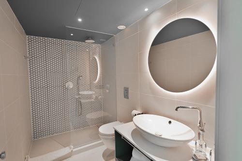 a bathroom with a sink and a mirror and a toilet at AKOYA HOTEL in Eilat