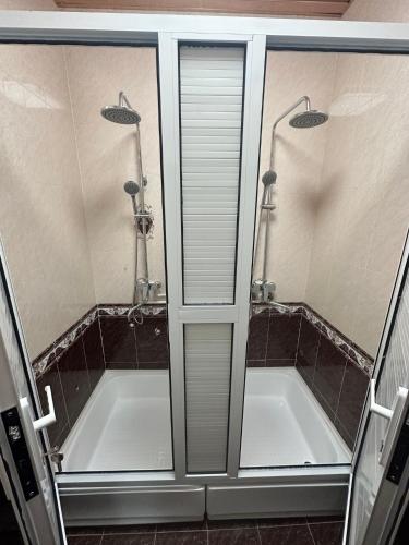 a bathroom with two sinks and a shower with glass doors at Palm Hostel in Tashkent