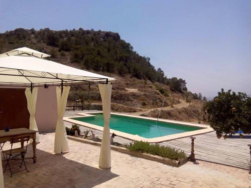 a large swimming pool with a pavilion next to a mountain at Guest House Guapas in La Garapacha
