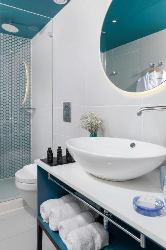 a bathroom with a sink and a toilet and a mirror at AKOYA HOTEL in Eilat