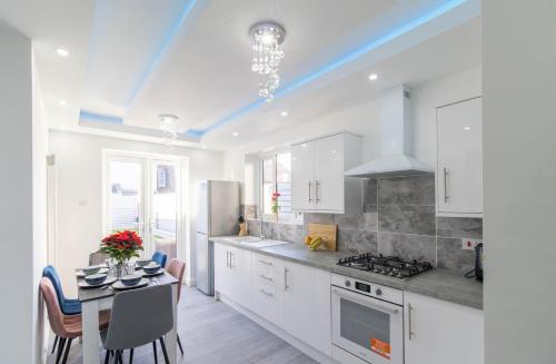 a kitchen with white cabinets and a table and a dining room at Open Mind Property - 6 Luxury Bedrooms with Free Parking in Portsmouth