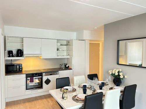 Luxurable super central 3 BR apt for a family of 6 in Oslo في أوسلو: مطبخ أبيض مع طاولة طعام وكراسي