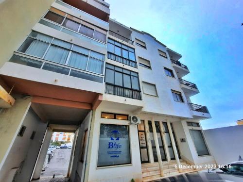 a white building with a blue sign on it at Blife Julya private rooms in Faro
