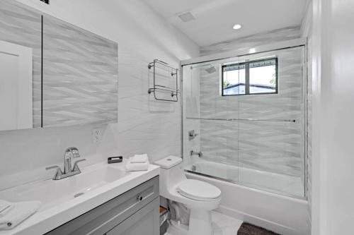 een witte badkamer met een toilet en een douche bij Modern Home, Heated Pool Hot-Tub, 12min to Ocean in Miami