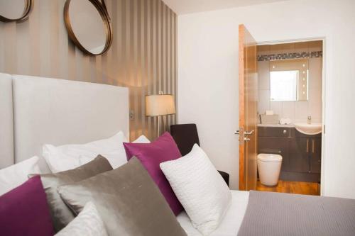 een slaapkamer met een bed met paarse en witte kussens bij Stylish and central two bedroom & two bathroom apartment with free parking in Bath