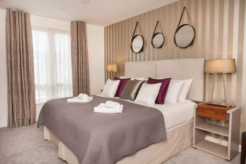 een slaapkamer met een groot bed en 2 handdoeken bij Stylish and central two bedroom & two bathroom apartment with free parking in Bath