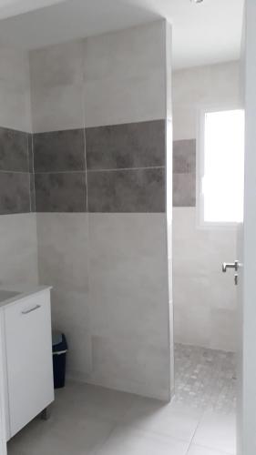 ein weißes Bad mit einer Dusche und einem Fenster in der Unterkunft Un petit coin de paradis in Barbâtre