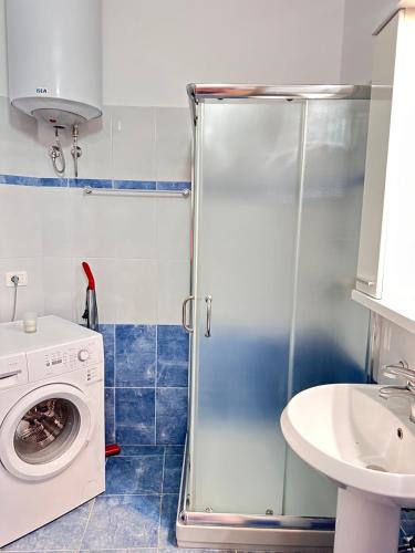 a bathroom with a washing machine and a sink at Violet Sea View Apartment in Sarandë